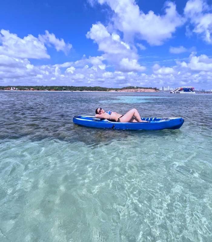 Mulher relaxando em caiaque nas águas claras da orla de João Pessoa