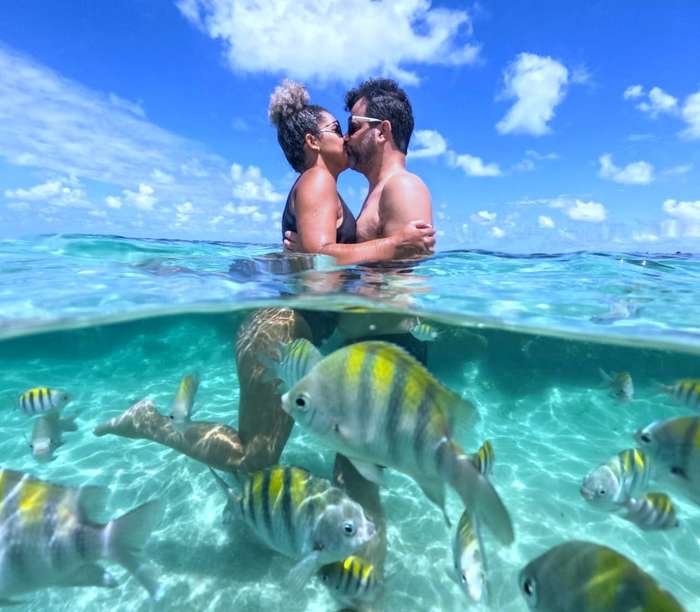 Casal na água das Piscinas Naturais do Seixas durante passeio em João Pessoa