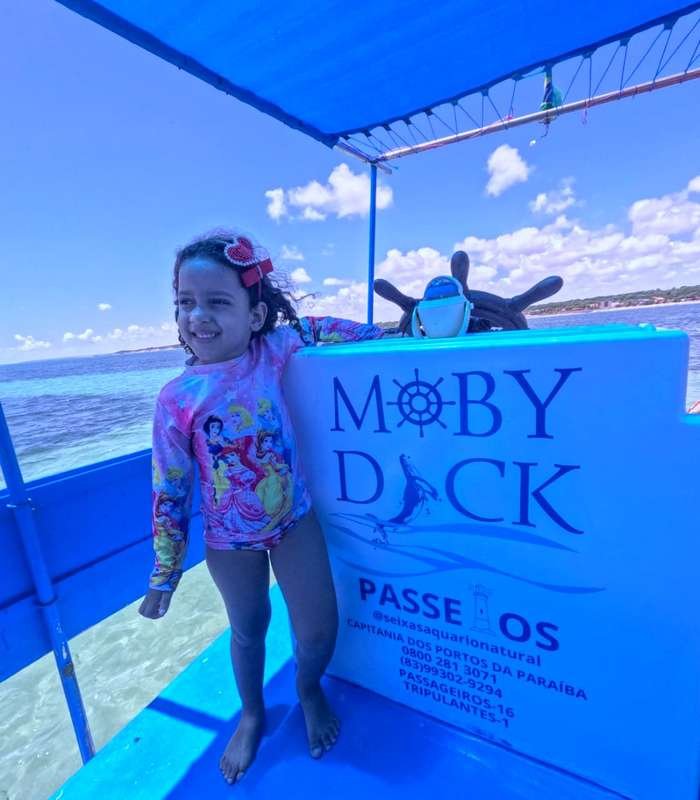Criança sorrindo a bordo do barco Moby Dick no passeio às Piscinas Naturais do Seixas
